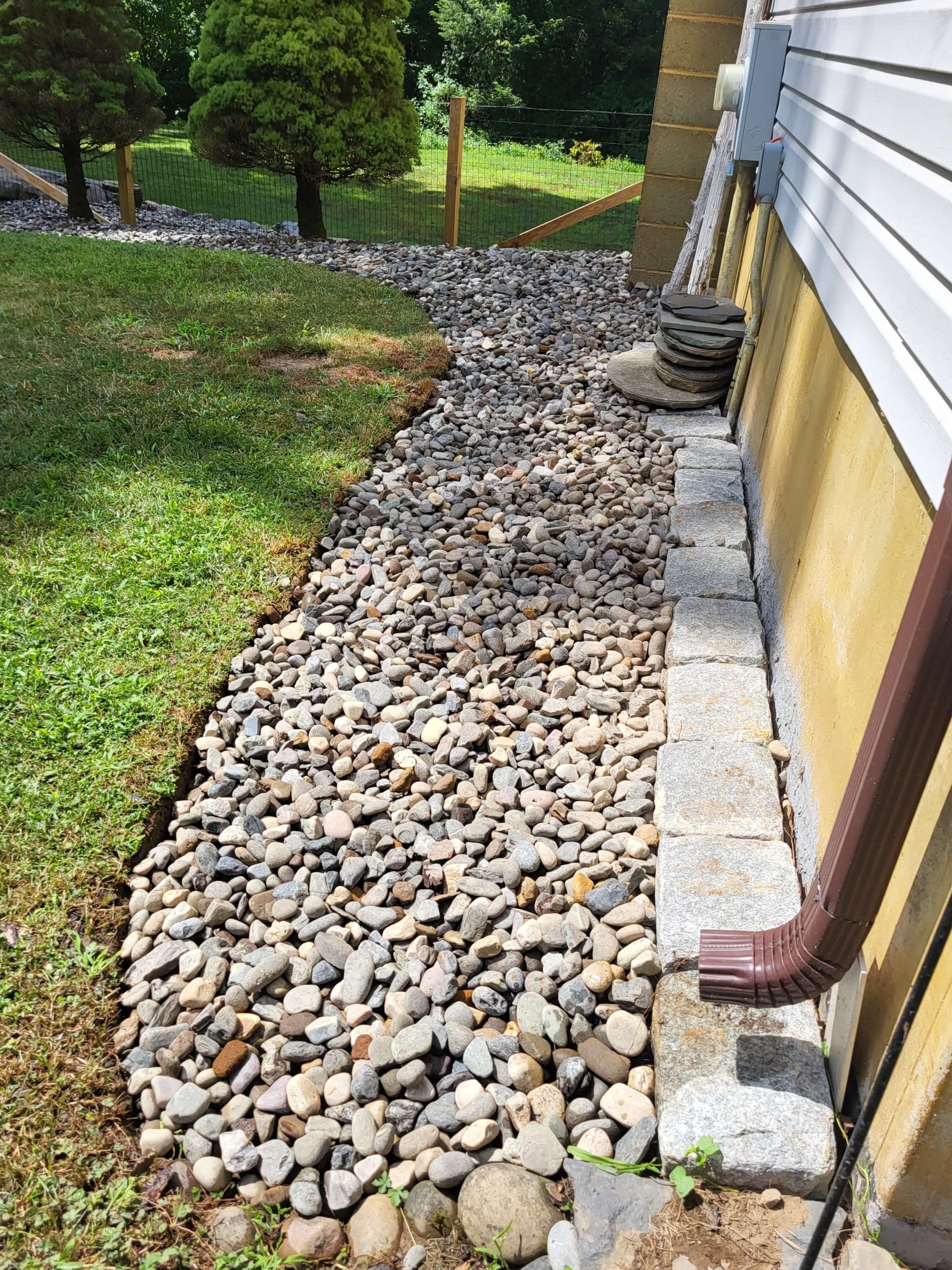 A winding gravel path adjacent to a house, surrounded by lush plants, inviting exploration of the outdoor space.